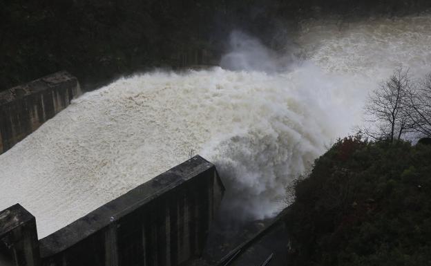 El agua saliendo por uno de los tres aliviaderos en el embalse de Tanes, en el municipio de Caso, ayer. :: DAMIÁN ARIENZA