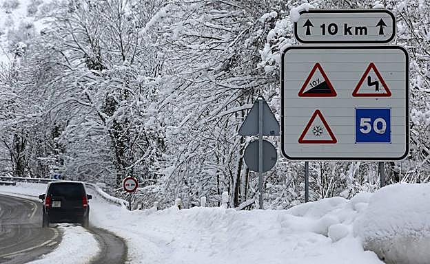 Un vehículo circula por el puerto de Pajares, cubierto por la nieve.