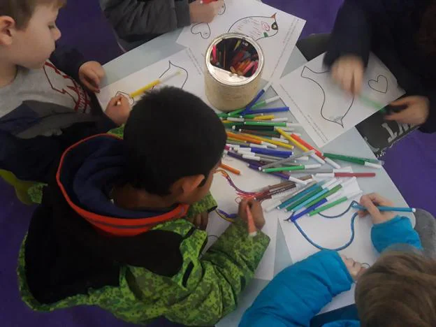 Varios niños colorean en el taller de la asociación Raitana. 