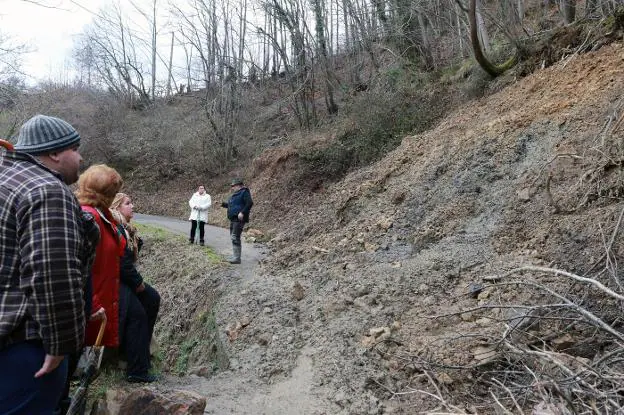 Algunos vecinos de La Llonga observan el argayo, que continúa cayendo sobre la carretera.