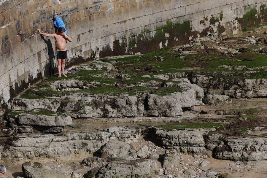 Decenas de personas se animaron a pasear por la Playa de San Lorenzo, bajo el sol y por la gran extensión de arena que dejó la bajamar