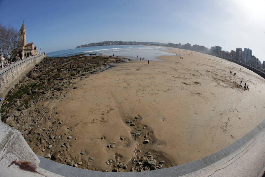 Decenas de personas se animaron a pasear por la Playa de San Lorenzo, bajo el sol y por la gran extensión de arena que dejó la bajamar