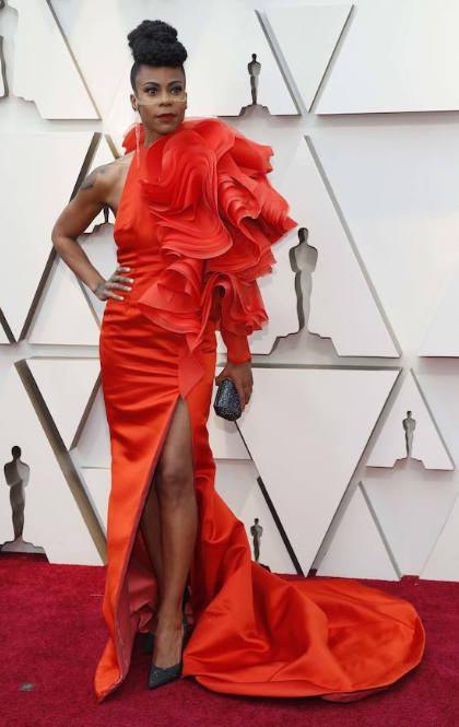 Hannah Beachler ha sobrecargado su estilismo con un vestido en color naranja muy barroco. La diseñadora de producción en 'Black Panther' ha aparecido con un vestido de cuello ‘halter’ y con una abertura en la falda complementado con un extravagante juego de volúmenes y volantes en una de las mangas.