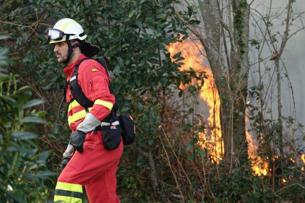 Un integrante de la UME pasa por una zona afectada por el fuego en Naves. 