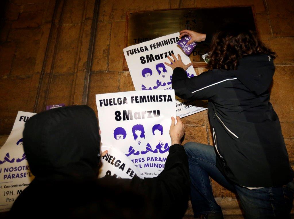 Un veintena de personas comenzó la jornada de huelga general feminista con una pega de carteles convocando a la manifestación de esta tarde en Gijón