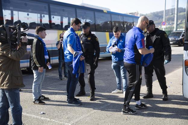 Varios aficionados del conjunto azul, a la salida de Oviedo, son cacheados por dos policías nacionales. 