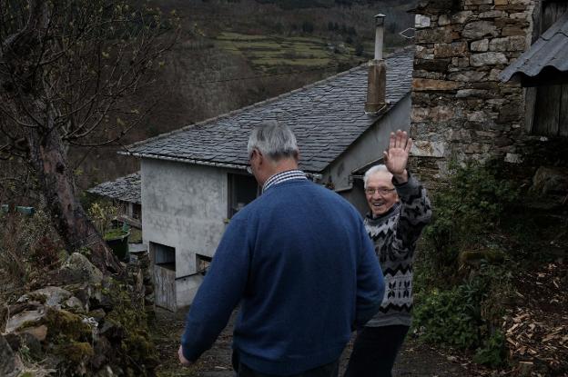 Donato Álvarez (88 años) saluda al regresar a su casa junto a uno de los 'emigrantes' que está de visita, Manuel Fuertes. 