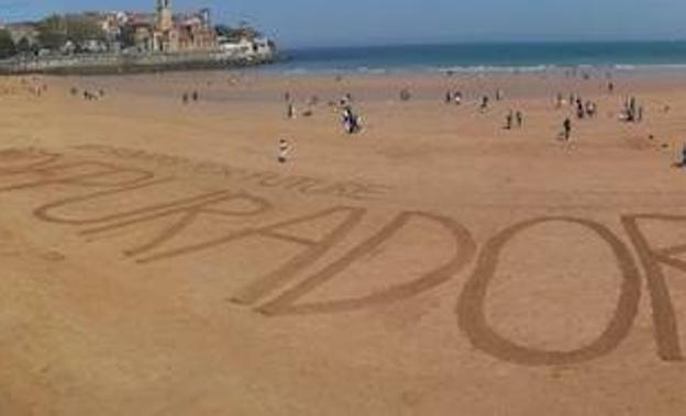 Parte del enorme rótulo de arena en la playa de San Lorenzo reivindicando la puesta en marcha de la depuradora del este.