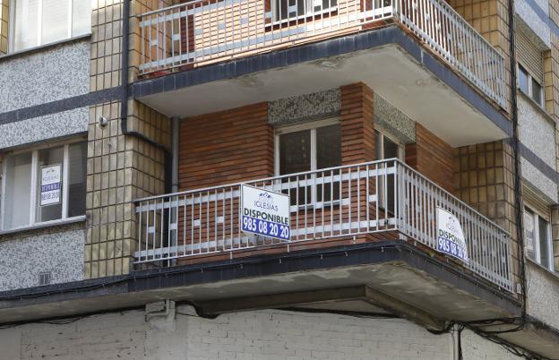 Imagen de una vivienda gijonesa con carteles que indican su condición de piso disponible. 