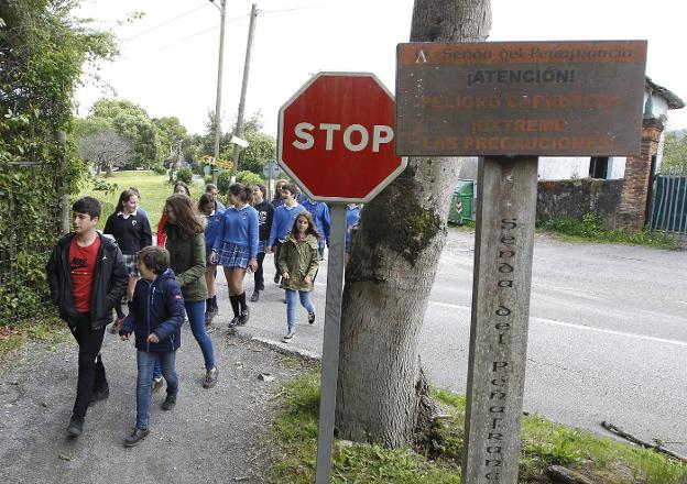 Un grupo de niños cruza la carretera que carece de pasos de peatones. 