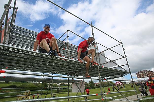 Dos de los participantes saltan sobre una estructura de andamios. 