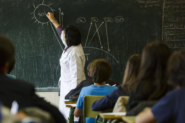 Una profesora dibuja en la pizarra durante una clase. 