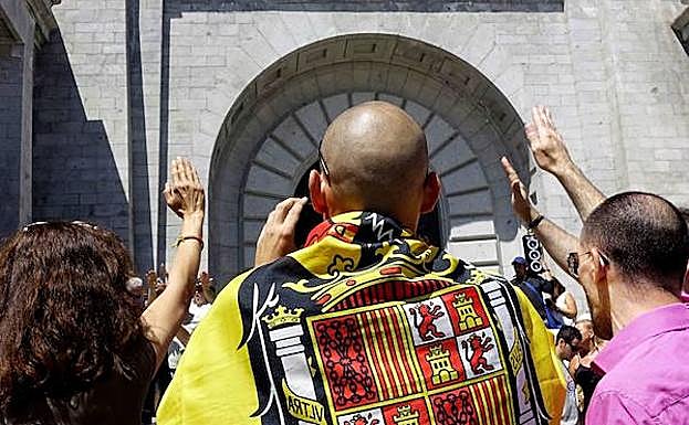 Varias personas saludan con el brazo en alto frente a la basílica del Valle de los Caídos.