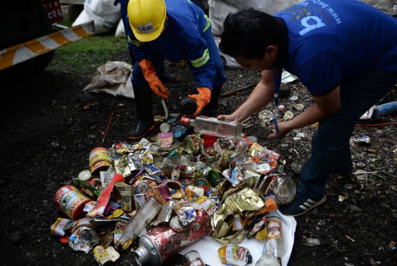 Los trabajadores nepalíes buscan materiales reciclables de una pila de desechos recolectados en el monte Everest, en Katmandú
