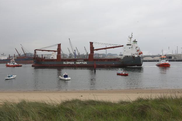 Un buque de Sloman Neptun maniobra en la ría de Avilés, asistido por dos remolcadores, frente a la playa de San Balandrán. 