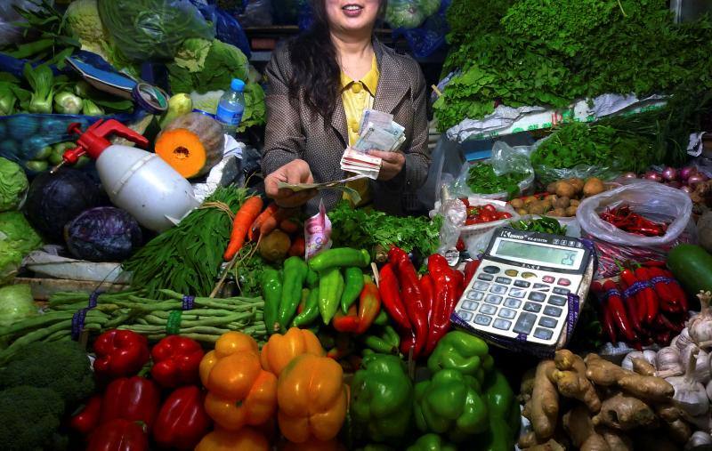 La propietaria de un establecimiento de fruta y verdura atiende a una clienta en un pequeño mercado de Pekín.