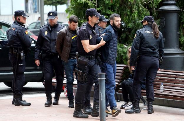 Los detenidos escoltados por los agentes y en el banco, la mujer, tambien arrestada. 