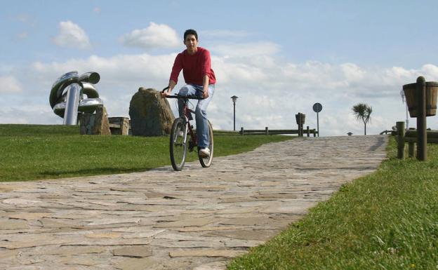 Un ciclista en el paseo, con la escultura 'Solidaridad', de Pepe Noja.