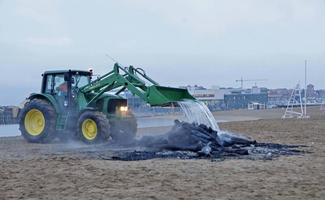 Un tractor de la empresa municipal apagando el fuego que quedó en la playa.