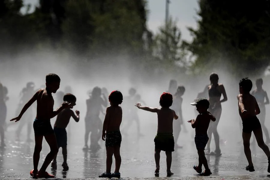 Un grupo de niños se bañan hoy en las fuentes verticales del Madrid Rio.