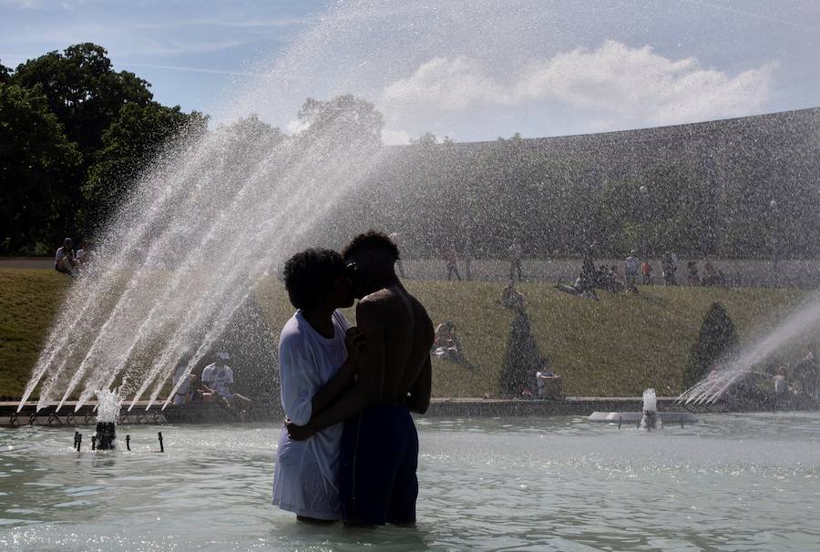 Una pareja se refresca con el agua de la fuente de la Plaza del Trocadero, frente a la Torre Eiffel, durante la ola de calor que recorre París este martes (Francia). Las temperaturas llegarán a los 40 grados centígrados esta semana.