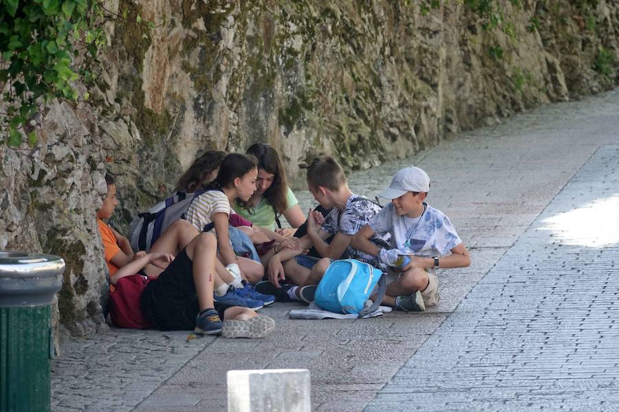 Un grupo de jóvenes se refugia en la sombra del calor en Llanes.