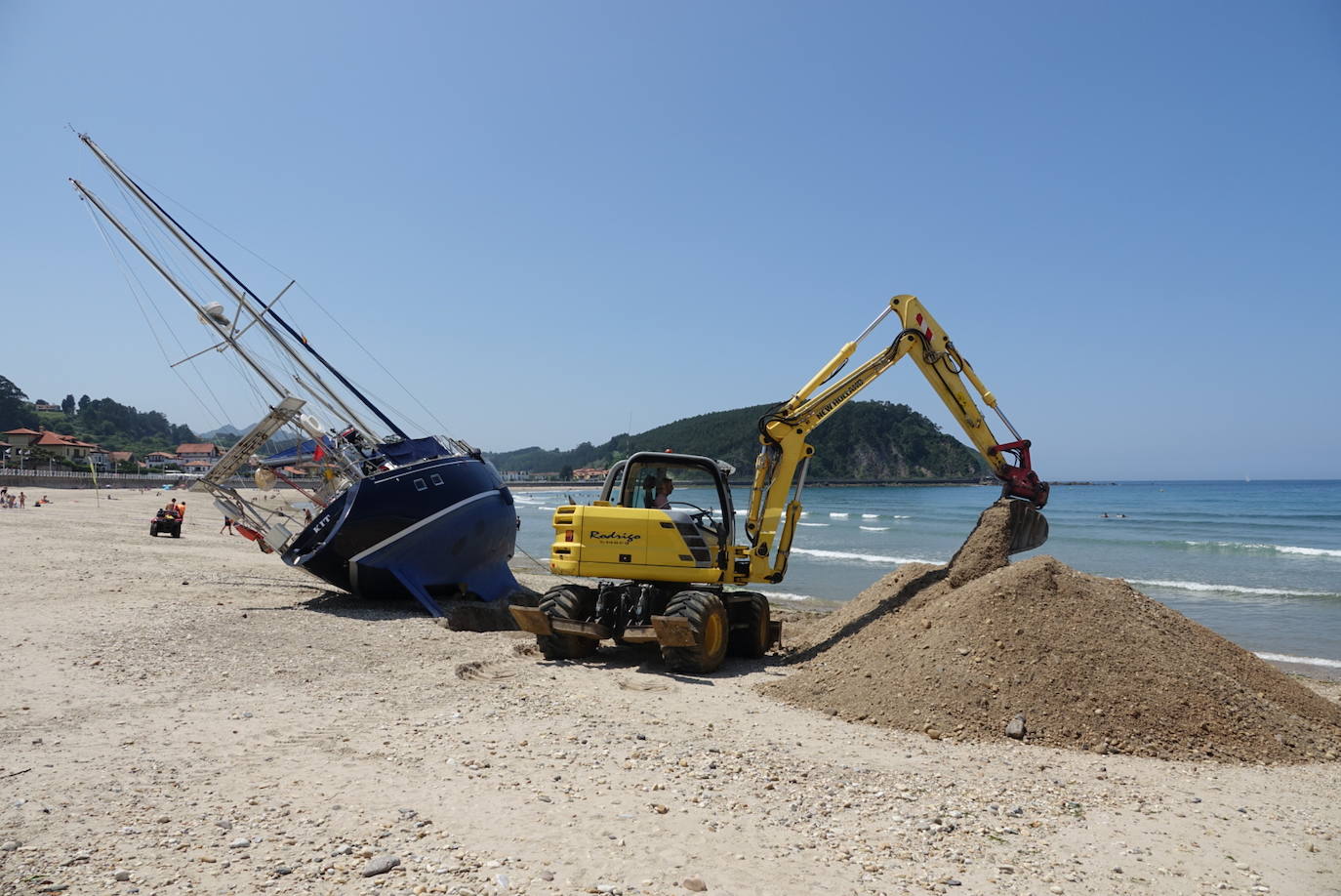 Una excavadora abre un canal en la playa de Santa Marina para intentar facilitar el posterior arrastre en pleamar del barco varado