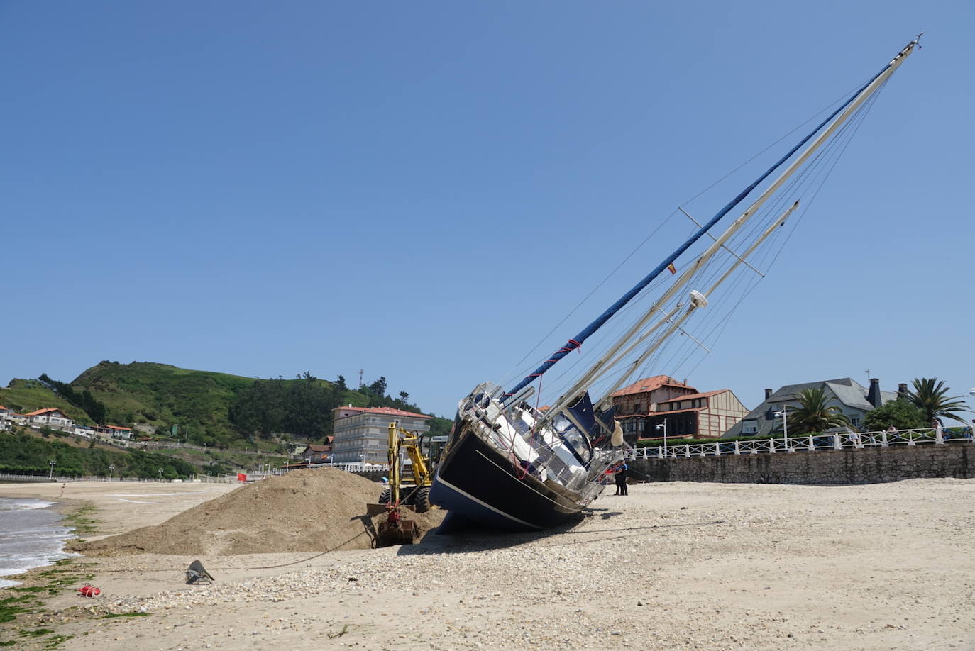 Una excavadora abre un canal en la playa de Santa Marina para intentar facilitar el posterior arrastre en pleamar del barco varado