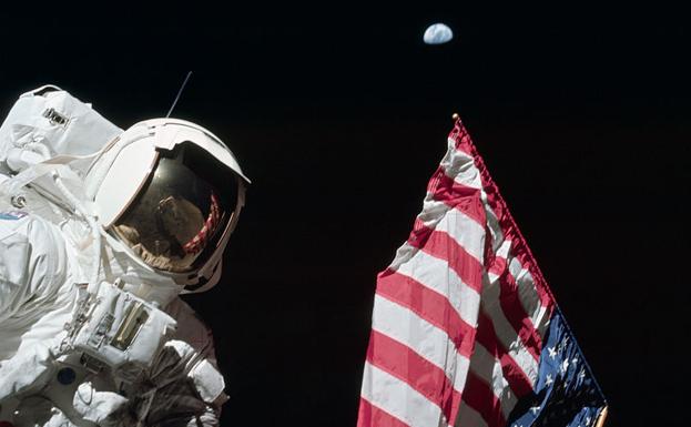 Harrison Schmitt posa con la bandera estadounidense y la Tierra al fondo.