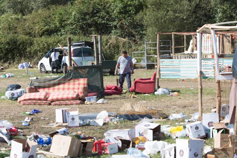 La multitudinaria fiesta del Xiringüelu ha dejado toneladas de basura en el prau Salcéu. Botellas, vasos, y restos de las coloridas casetas que son seña de identidad de la celebración han quedado esparcidos por el campo a la espera de que se retiren, unas labores que ya han comenzado.