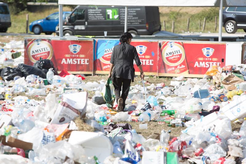 La multitudinaria fiesta del Xiringüelu ha dejado toneladas de basura en el prau Salcéu. Botellas, vasos, y restos de las coloridas casetas que son seña de identidad de la celebración han quedado esparcidos por el campo a la espera de que se retiren, unas labores que ya han comenzado.