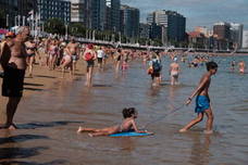 Un baño en la playa para combatir el calor en Gijón