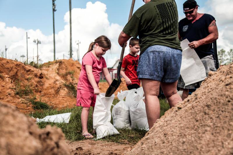 Dos niños colaboran poniendo sacos terreros para proteger sus viviendas de las posibles inundaciones en Middleburg, Florida.