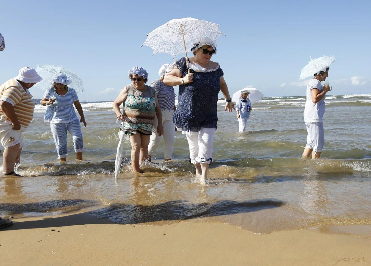 Varias de las integrantes de la asociación, ataviadas con trajes de época, mojan los pies en las aguas de San Lorenzo. 