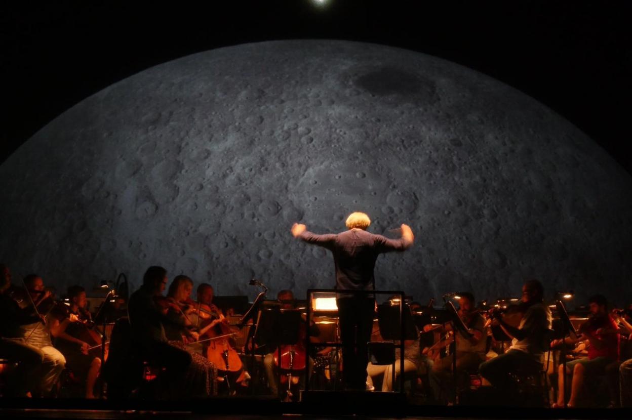 Proyecciones. Sobre estas líneas, el maestro Christoph Gedschold, dirige a la OSPA y Oviedo Filarmonía rodeado por algunas de las imágenes que envolverán a las orquestas y al público creando un efecto tridimensional. Junto a él, Carlos Wagner da indicaciones a los cantantes durante un ensayo. 