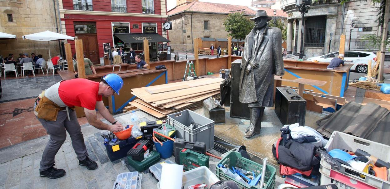 Un operario levantando un chiringuito en la plaza de Porlier, junto a la escultura de El Viajero. 
