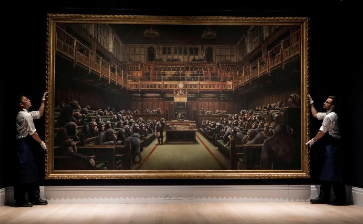 Los empleados de Sotheby's posan con la obra de Banksy 'Devolved Parliament'. 