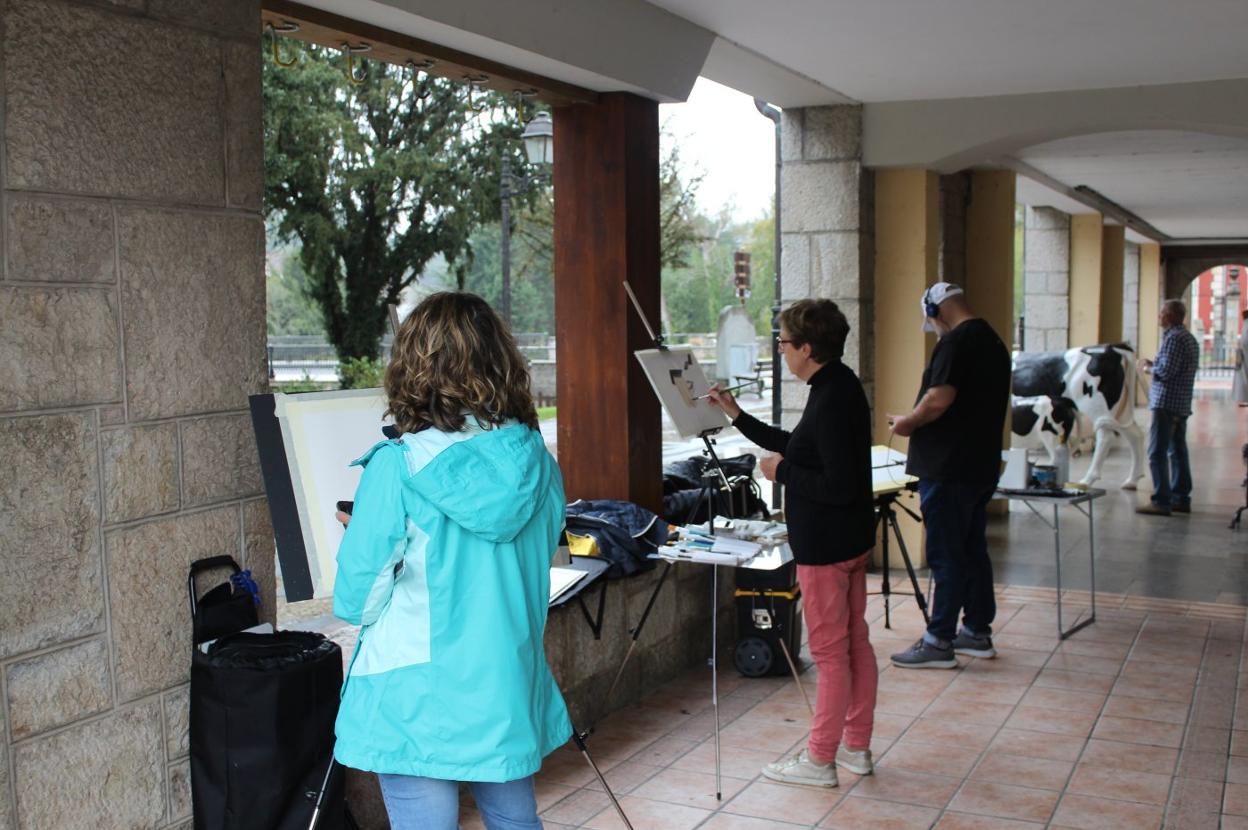 Pintores resguardados de la lluvia, ayer durante el concurso. 