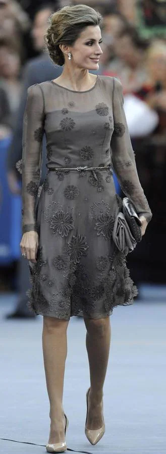 En 2011 Letizia se decantó por un diseño de muselina en un color marrón grisáceo con mangas de gasa y flores bordadas. Para este look, cambió esa coleta sencilla del año anterior por un recogido mucho más sofisticado para aportar aún más elegancia al look.