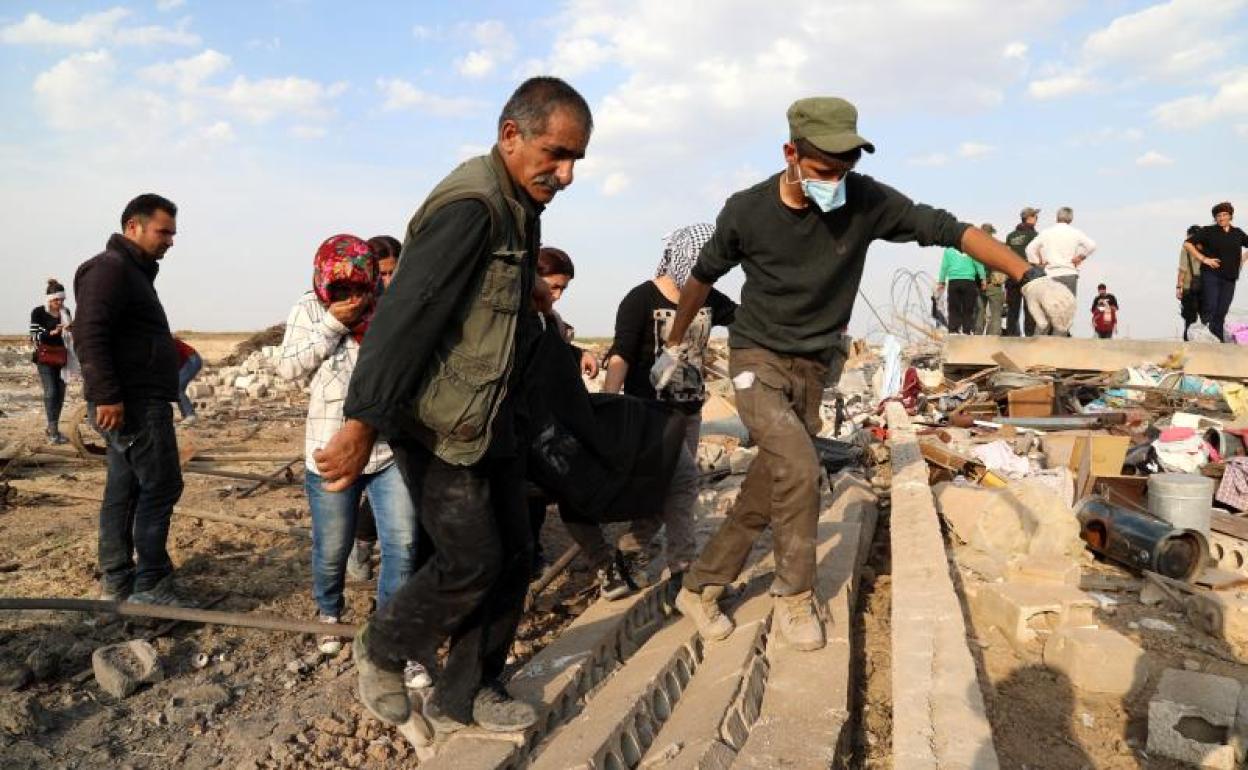 Hombres kurdos y voluntarios americanos trasladan un cuerpo en Ras al-Ain, una ciudad al norte de Siria. 