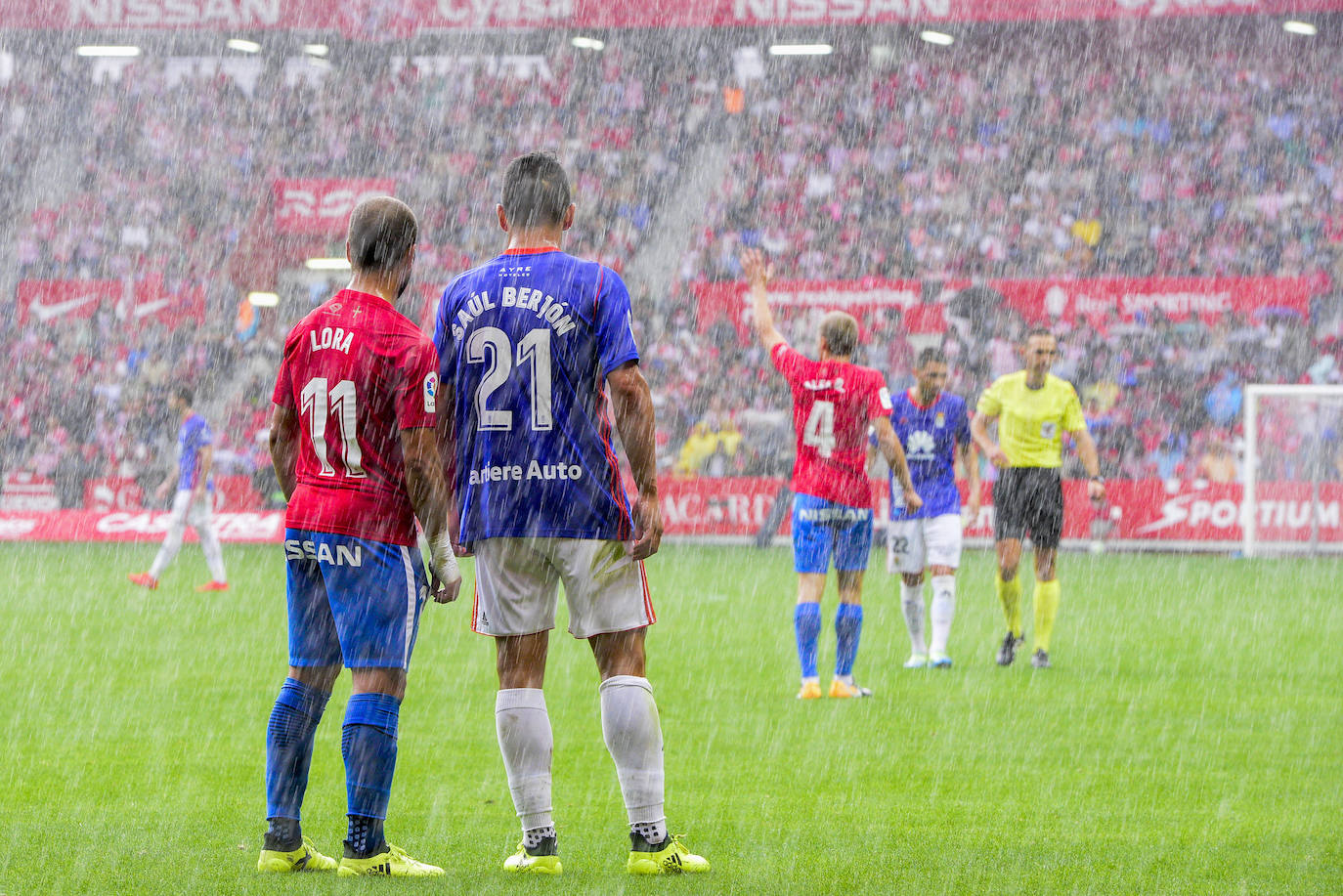 Lora y Saúl Berjón bajo la lluvia en el partido de Liga de Segunda División entre el Sporting y el Real Oviedo. 