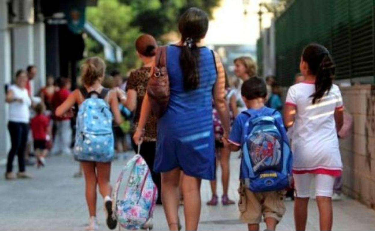 Una madre leva a sus hijos al colegio.