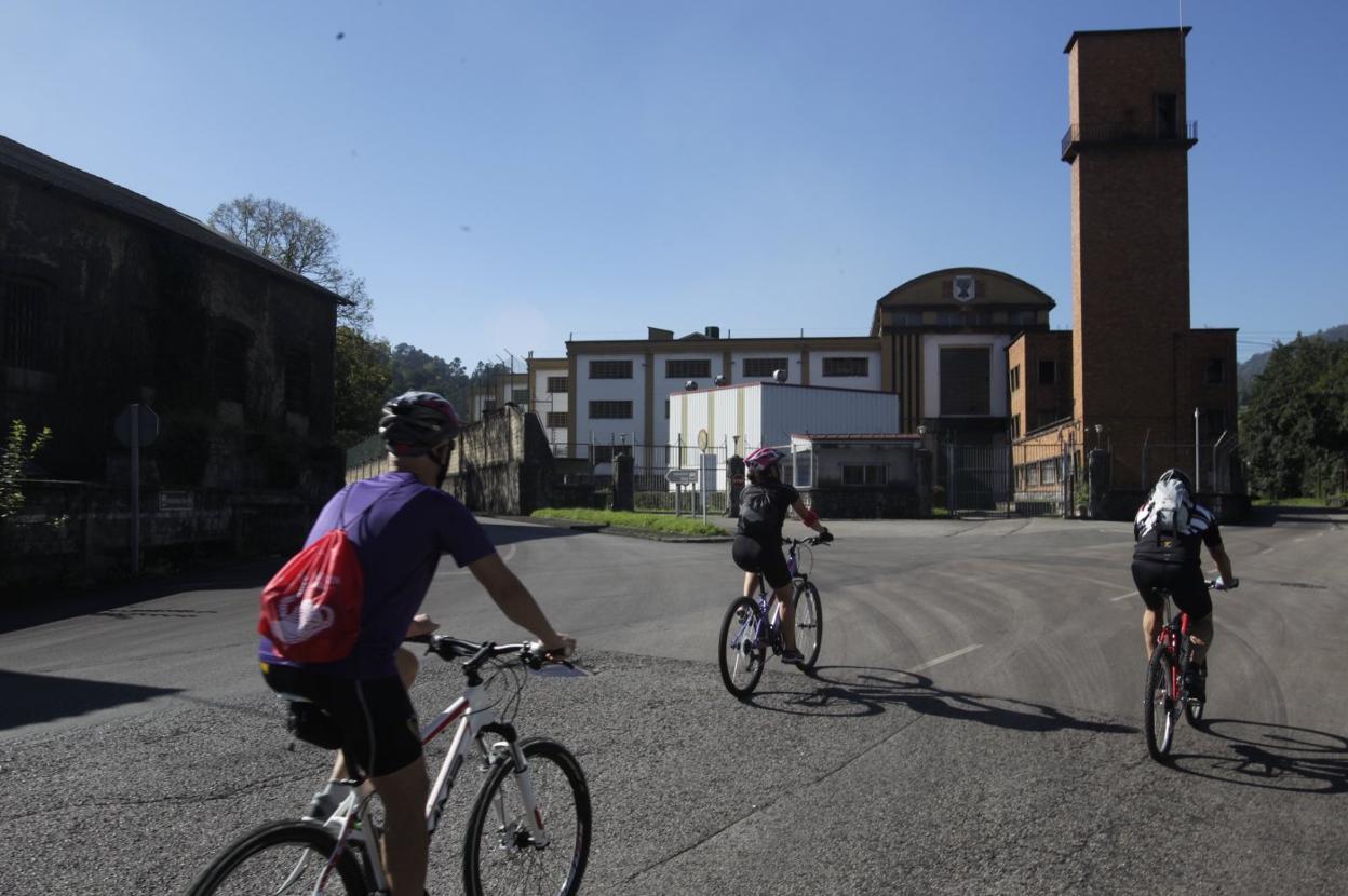 Unos ciclistas pasan ante el taller de municiones de Expal, en Trubia. 