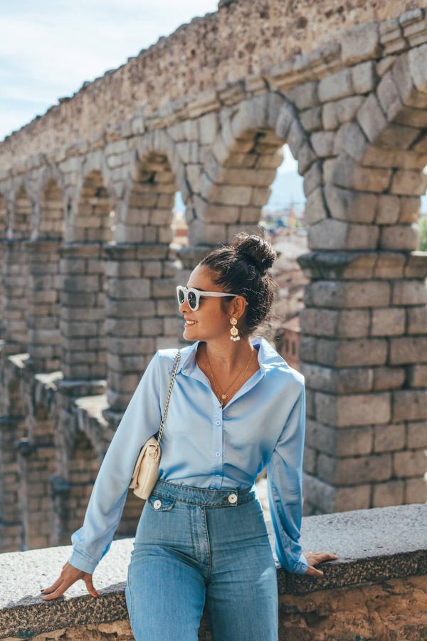 Viernes: Camisa con cuello solapa en azul claro con acabado satinado, jeans de tiro alto claros y bolso clutch en color crema.