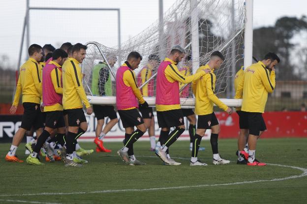 Los jugadores del Sporting trasladan una de las porterías durante la sesión a puerta cerrada en Mareo.