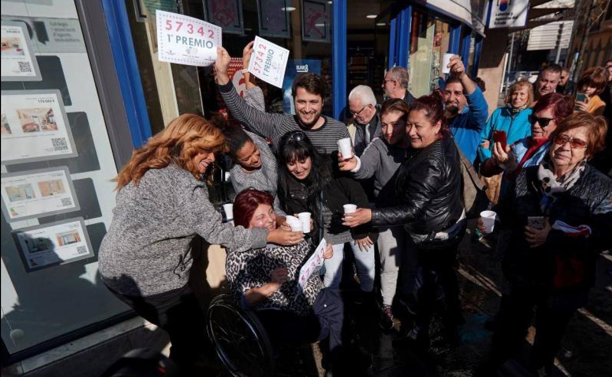 Varias personas festejan el primer premio del Sorteo extraordinario de El Niño, en la puerta de la administración de lotería de Mollet del Vallés, que ha repartido parte del primer premio, el 57342, en esta localidad barcelonesa.