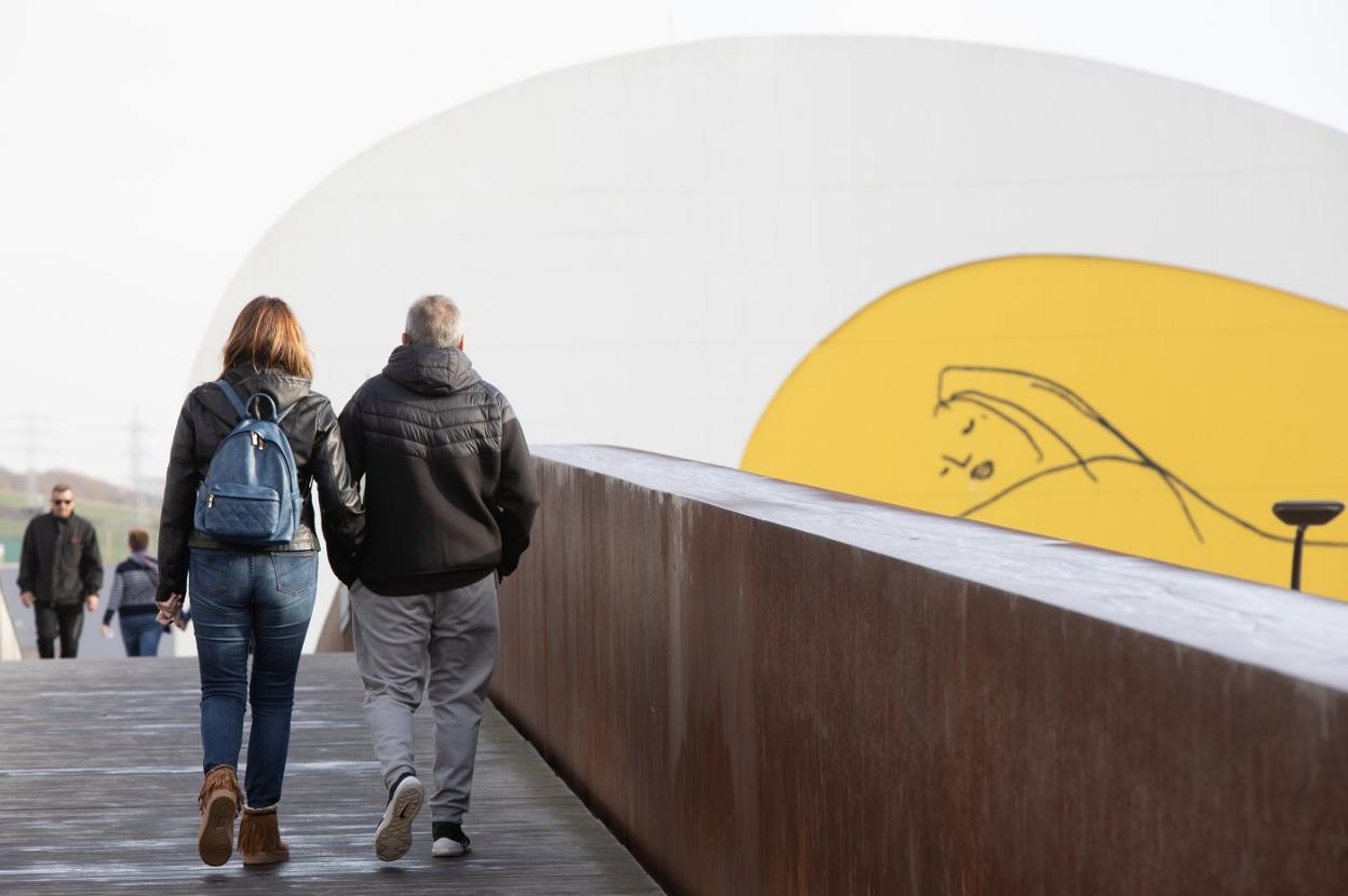 Dos turistas pasean por la pasarela que comunica el casco histórico de Avilés con el Centro Niemeyer. 