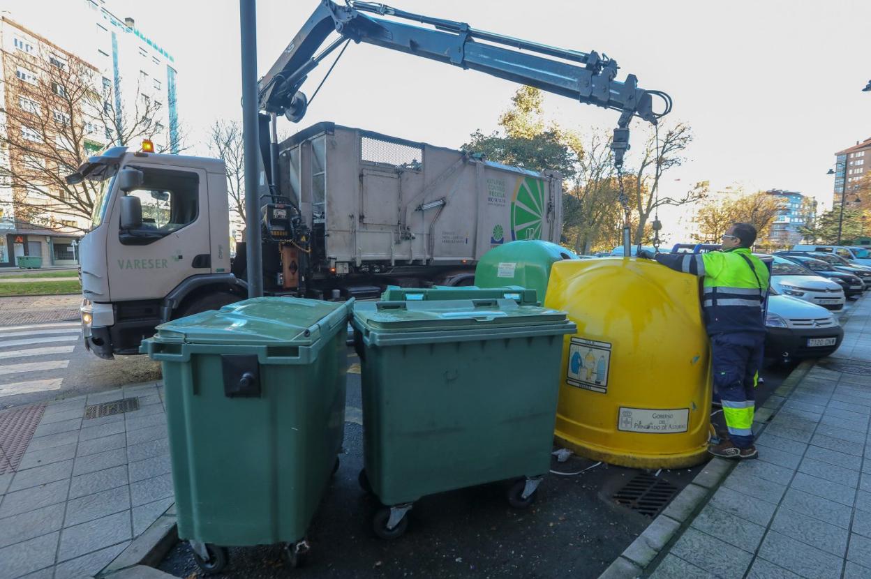 Un camión de Cogersa retira el vidrio de un contenedor de reciclaje. 