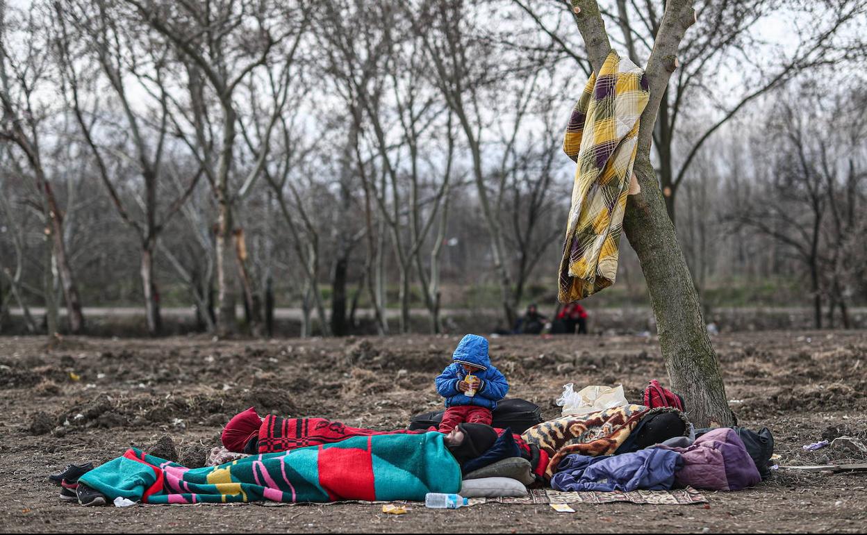 Un niño apura su desayuno mientra sus padres y hermanos duermen al raso en la frontera de Grecia con Turquía.