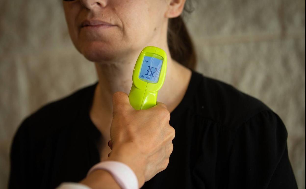 La recepcionista de una cadena de gimnasios de Barcelona toma la temperatura a una clienta.